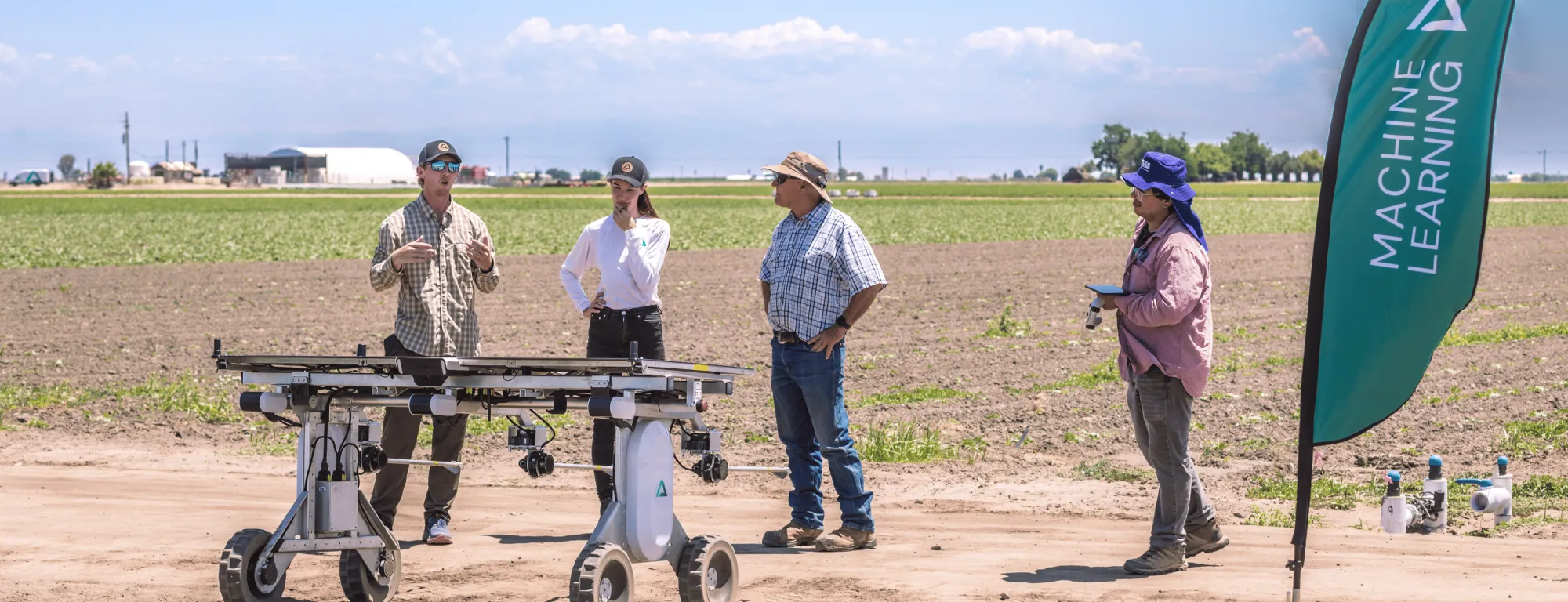 People stand in a field for a demonstration of a solar-powered robot providing chemical-free autonomous weed control