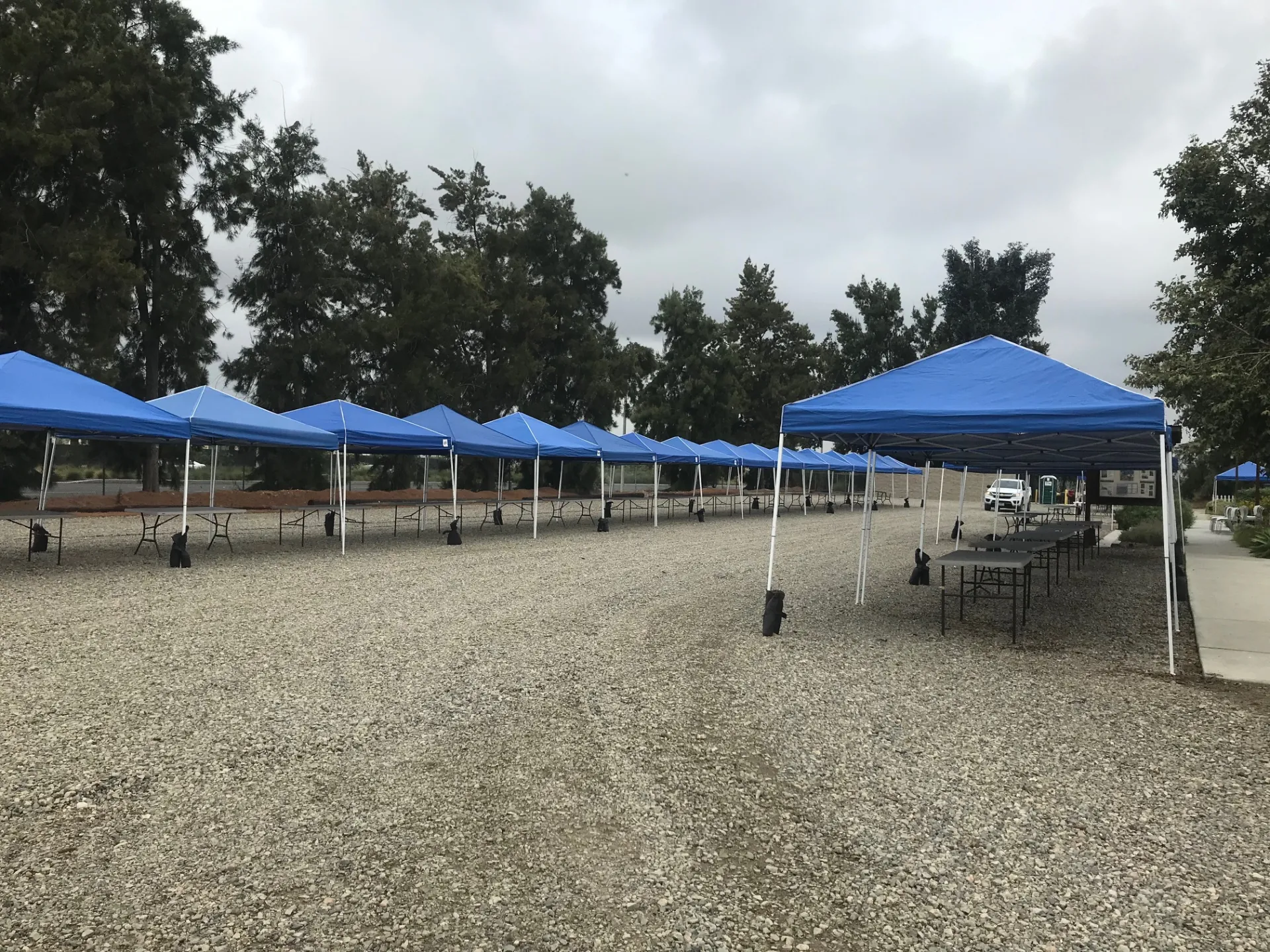 a gravel parking lot with blue tents set up for an event