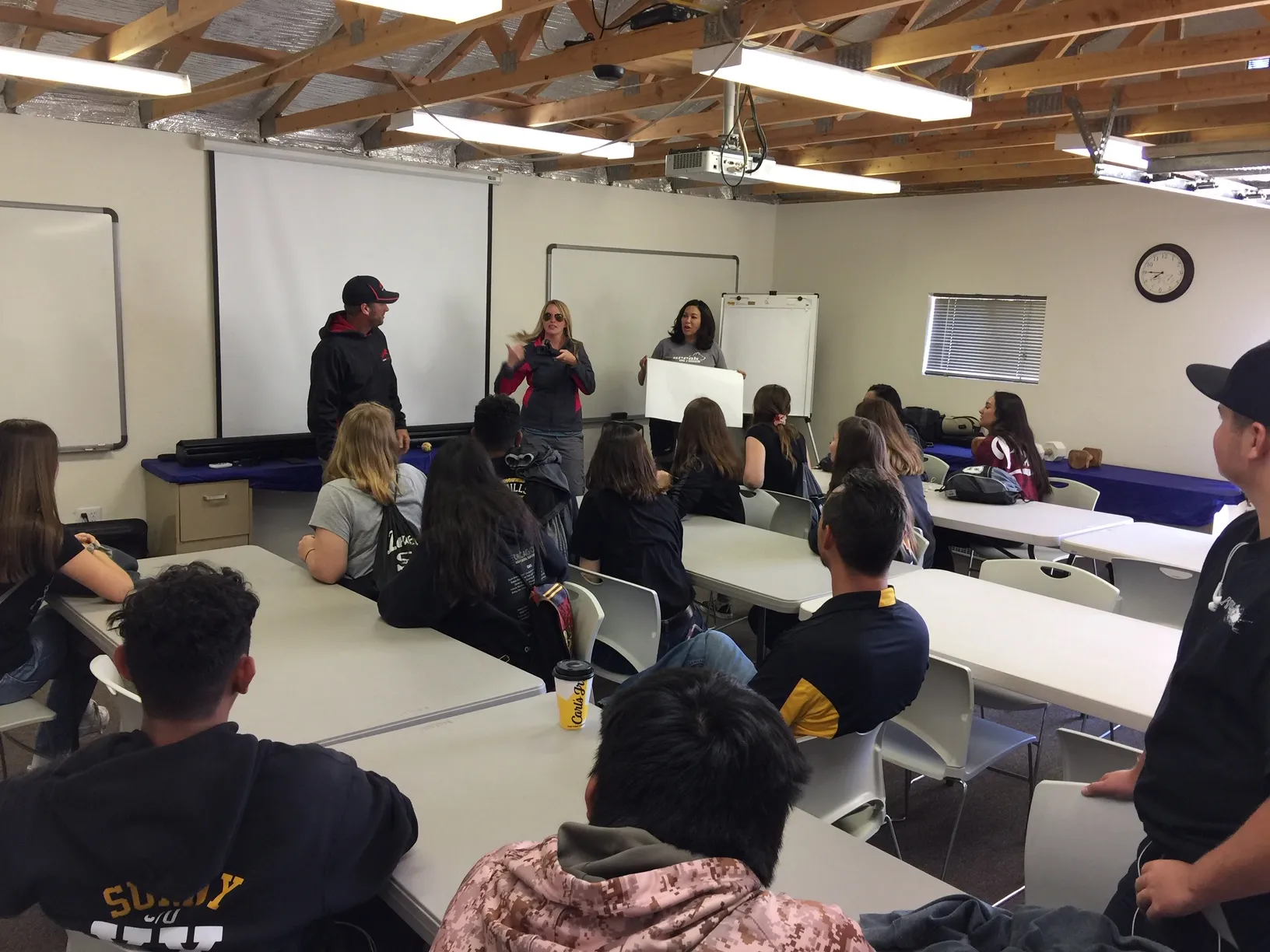 students seated in a classroom learning from 3 instructors