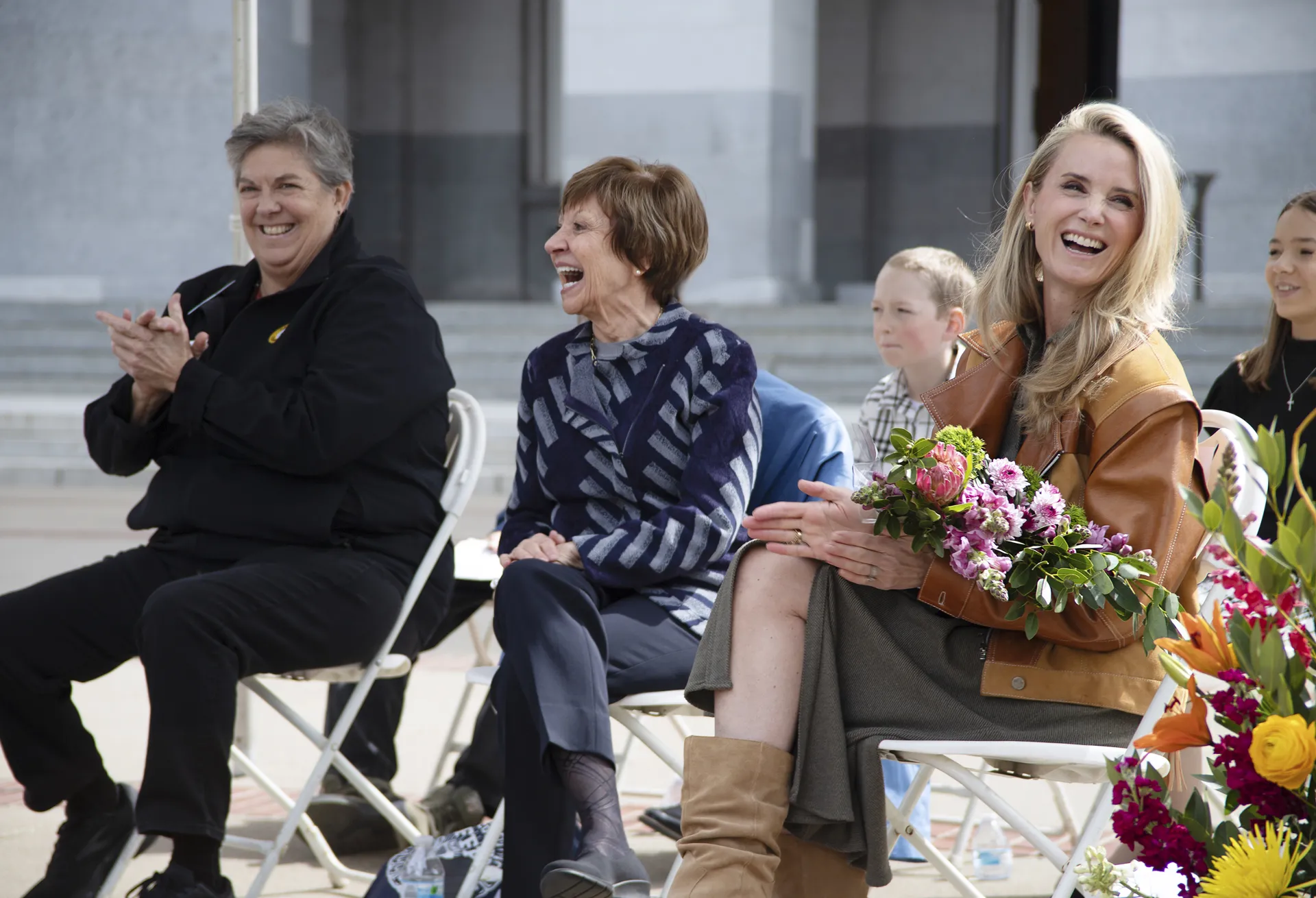 Three women laughing while sitting on stage
