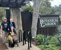 three people in front of the botanical garden sign