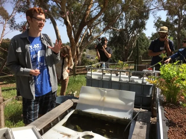 Un estudiante de UCSA habla sobre un sistema de circuito cerrado de acuaponía creado en el Huerto de Roger. Varios estudiantes de UCSD, así como miembros de la GFI conducen proyectos de investigación en el huerto con el objetivo de replicarlos y extenderse a huertos fuera de UCSD y en la comunidad.