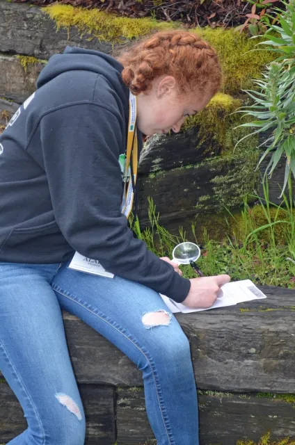 Girl outdoors writing on a paper