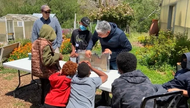 Sam Sandoval Solis, especialista de la Extensión Cooperative de la UC, en el centro, demuestra a los alumnos de quinto grado cómo el agua superficial fluye hacia el agua subterránea.