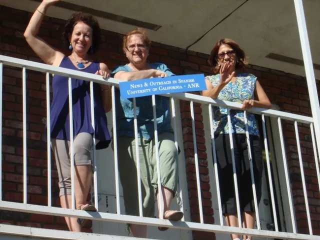 Three woman pose with a sign that says: