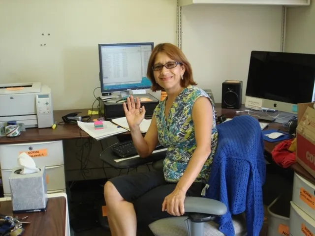 Norma sitting at her desk.