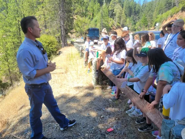 A man talks to a group of children at a reservoir