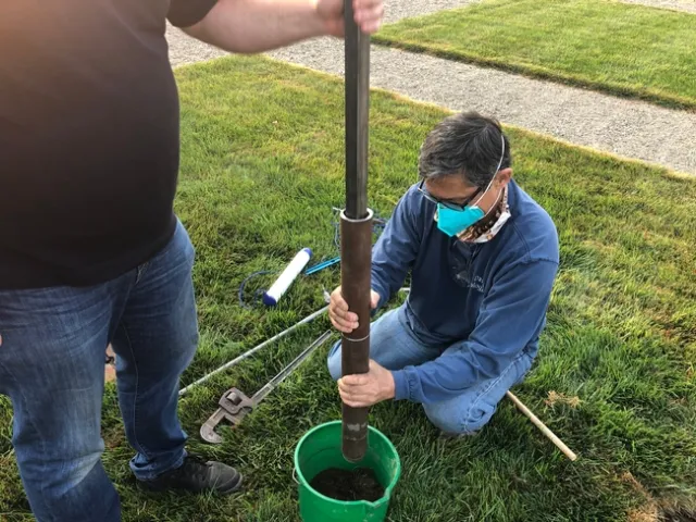 A man digs a hole to install a tube.