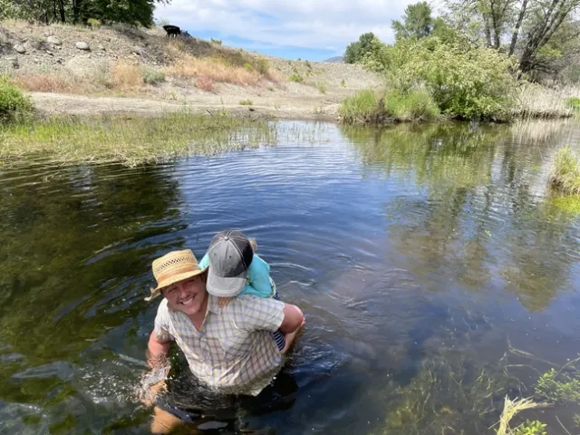Cleo Woelfle-Hazard and his child wade in water while visiting a beaver dam analog