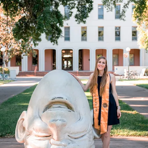 Jessica Macaluso stands next to Robert Arneson's egghead sculpture at Mrak Hall, UC Davis. She is scheduled to receive her bachelor's degree in the fall of 2020 in psychology with a biological emphasis.