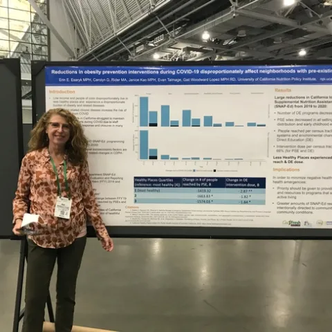 Gail Woodward-Lopez stands by a poster in Boston
