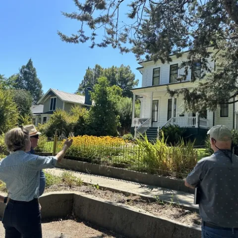 A UCCE advisor points to a house as she discusses home hardening options