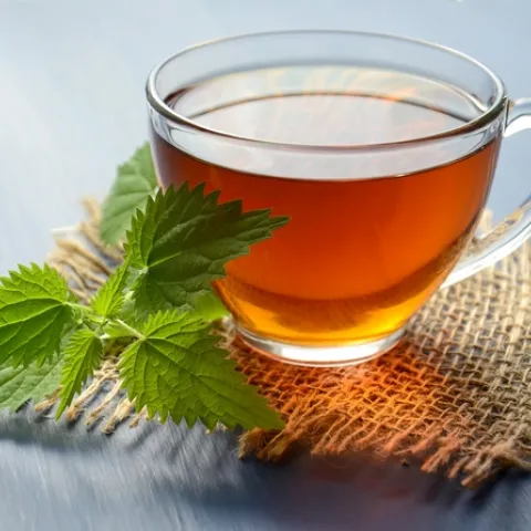 A cup of herb tea on a burlap coaster.