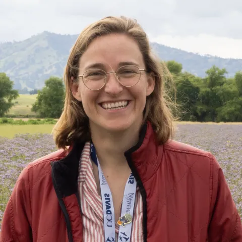 A person in a red jacket in a field of flowers.