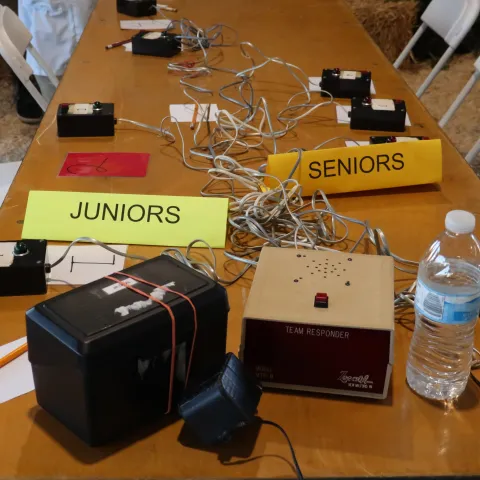 Placards read "junior" and "senior" on a table with buzzers and other equipment