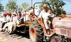 Clyde Kelly and son Jonathan drive the tractor-pulled hay wagon on a guided farm tour.