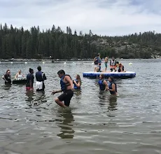 Lake with youth in water and on top of a floating inflatable dock.