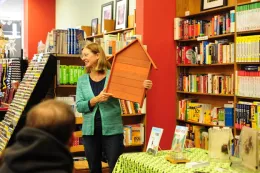 Smiling advisor holding wooden bat box to show audience.