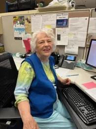 Woman wearing a blue vest, smiling.