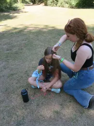 Two youth members braiding each others hair at resident camp