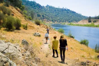 People hiking along a trail next to the Yuba River to view fall run Chinook Salmon spawning
