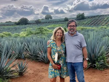 Lisa y Stuart Woolf aparecen frente a las plantas de agave. Los granjeros del Valle Central tienen una parcela de pruebas de la planta de agave. Fotografía cortesía de Stuart Woolf