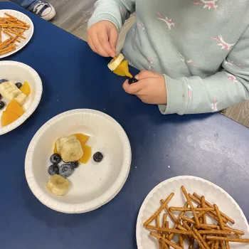 A child selects fruits from several plates