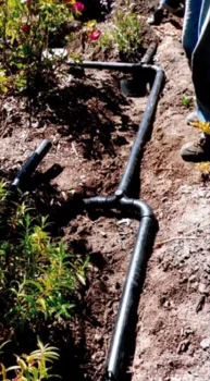 A photo of a garden that’s been dug up for a graywater system, where the pipes are branching to different areas of the garden