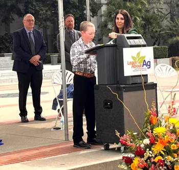 Josiah reading his story at a podium in front of the State Capitol