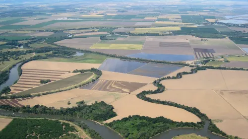 Ag fields between a winding river and mountains in the distance