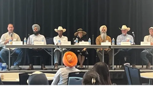 Seven farmers sitting at a long table on stage facing the audience